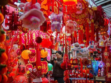 Seorang pembeli memotret dekorasi Tahun Baru Imlek di sebuah pasar di Beijing, China, Rabu 4 Februari 2026. Imlek merupakan sebuah perayaan yang sangat penting bagi masyarakat China. Perayaan tahun baru ini didasarkan oleh penanggalan lunar (bulan). (AP Photo/Vincent Thian)
