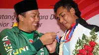 Menpora menyambut kedatangan Zohri di Indonesia dengan kalungan bunga, mengenakan jaket Asian Games 2018 dan menyerahkan secara simbolis uang bonus pembinaan.
