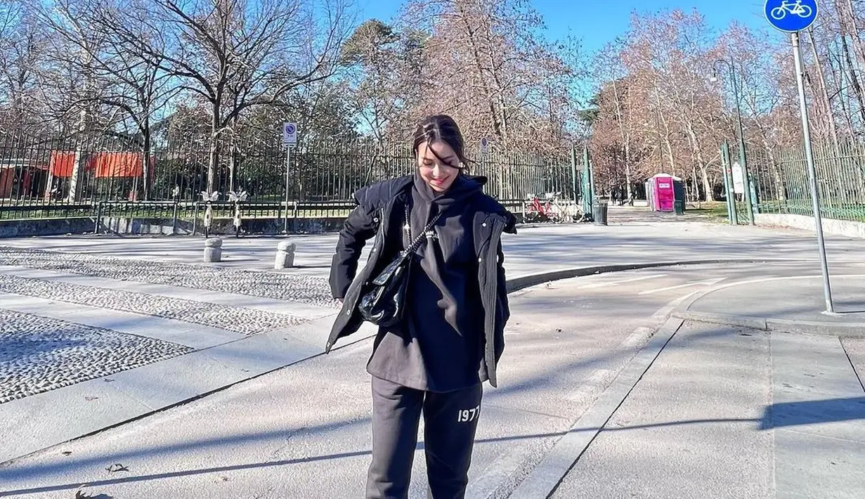 Selalu menarik melihat potret OOTD Ayu Ting Ting ketika ia berlibur. Salah satunya di foto ini, gaya kasual Ayu Ting Ting yang bisa jadi inspirasi. Ia memilih tampilan kasual dengan all black outfit, hoodie dirangkap lagi dengan vest, jogger pants, dan sling bag yang semuanya berwarna hitam, dipadu sneakers putih yang pas. Foto: Instagram.