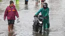 Warga berusaha melintasi genangan air ketika banjir merendam Jalan KH. Hasyim Ashari, Tangerang, Banten, Sabtu (16/7/2022). Akibat luapan kali angke ruas jalan yang menghubungkan Tangerang-Jakarta itu terputus akibat banjir. (Liputan6.com/Angga Yuniar)