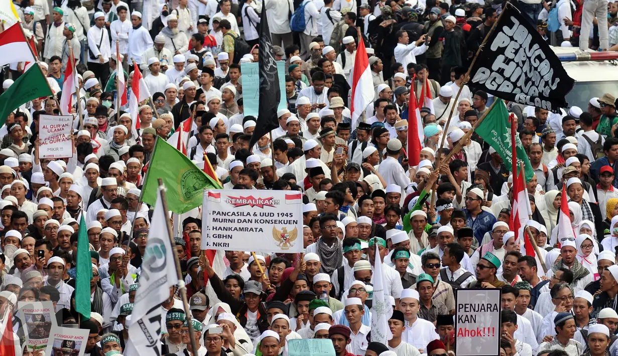 Ratusan ribu massa aksi damai membentangkan tulisan dan memenuhi ruas Jalan Merdeka Barat, Jakarta, Jumat (4/11). Massa melakukan aksi di depan Istana Negara menuntut penegakan hukum kasus dugaan penistaan agama. (Liputan6.com/Helmi Fithriansyah)