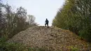 Aktivis lingkungan merekam konten untuk media sosial di tumpukan besar sampah yang dibuang sembarangan, yang ditumpuk di sebuah ladang antara Sungai Cherwell dan Jalan A34 dekat Kidlington, Oxfordshire, di barat London pada 16 November 2025. Gunungan atau tumpukan sampah ilegal berukuran raksasa ditemukan di sebuah ladang di tepi Sungai Cherwell dekat Kidlington, Oxfordshire, Inggris. (Justin TALLIS/AFP)