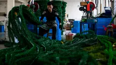 Seorang pekerja menyelesaikan pembuatan pohon Natal di pabrik Sun Xudan, Yiwu, China (7/12). Sun Xudan adalah pabrik terbesar di China yang memproduksi berbagai aksesoris Natal, termasuk pohon cemara buatan. (AFP Photo/Johannes Eisele)