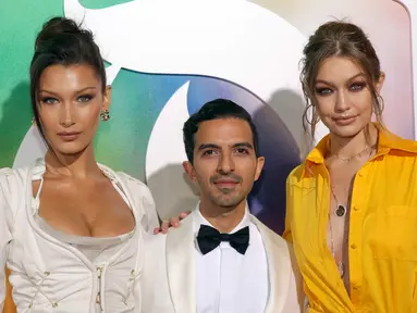 Supermodel Bella Hadid (kiri) dan model Gigi Hadid (kanan) bersama Founder & Editor-In-Chief The Business of Fashion Imran Amed (tengah) saat menghadiri New York Fashion Week (NYFW), Minggu (9/9). (Photo by Brent N. Clarke/Invision/AP)