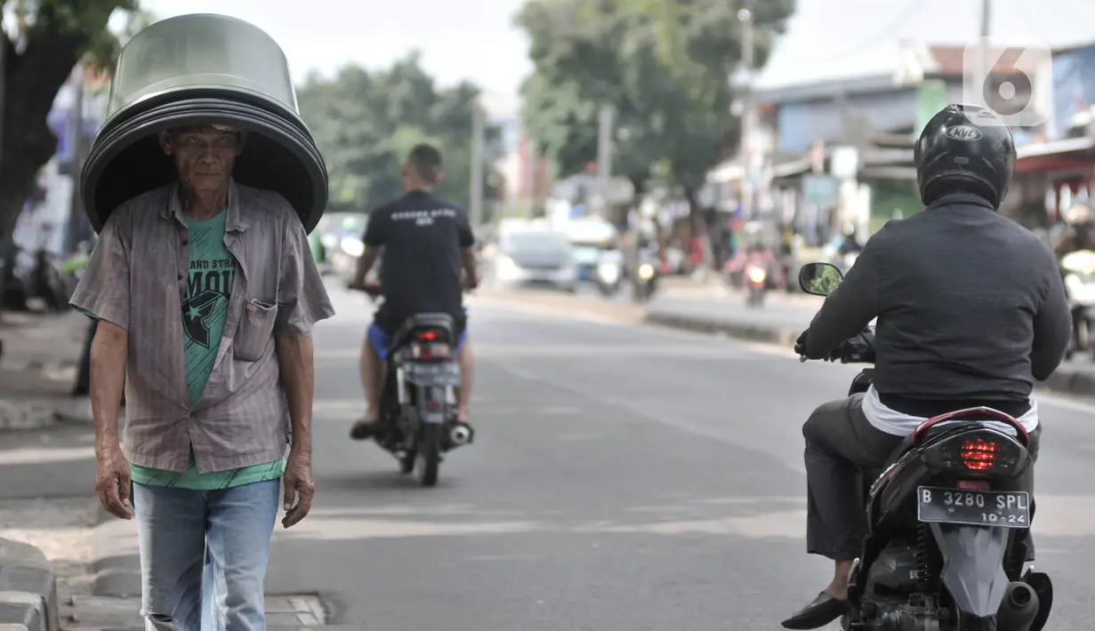 Pedagang tanpa mengenakan masker saat melintas di kawasan Pasar Minggu, Jakarta, Rabu (8/4/2020). Organisasi Kesehatan Dunia (WHO) telah merekomendasikan agar siapa saja menggunakan masker saat berada di tempat umum demi memutus mata rantai penyebaran virus Corona. (merdeka.com/Iqbal Nugroho)