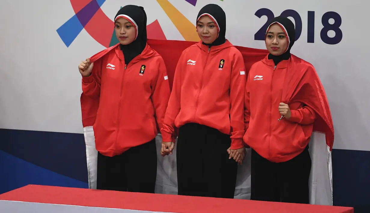 Tim pencak silat seni beregu putri Indonesia, Pramudita Yuristya (kiri), Lutfi Nurhasanah (tengah) dan Gina Tri Lestari (kanan) bersiap menerima medali emas Asian Games 2018, Jakarta, Rabu (29/8). (ANTARA FOTO/INASGOC/Melvinas Priananda/nak/18)