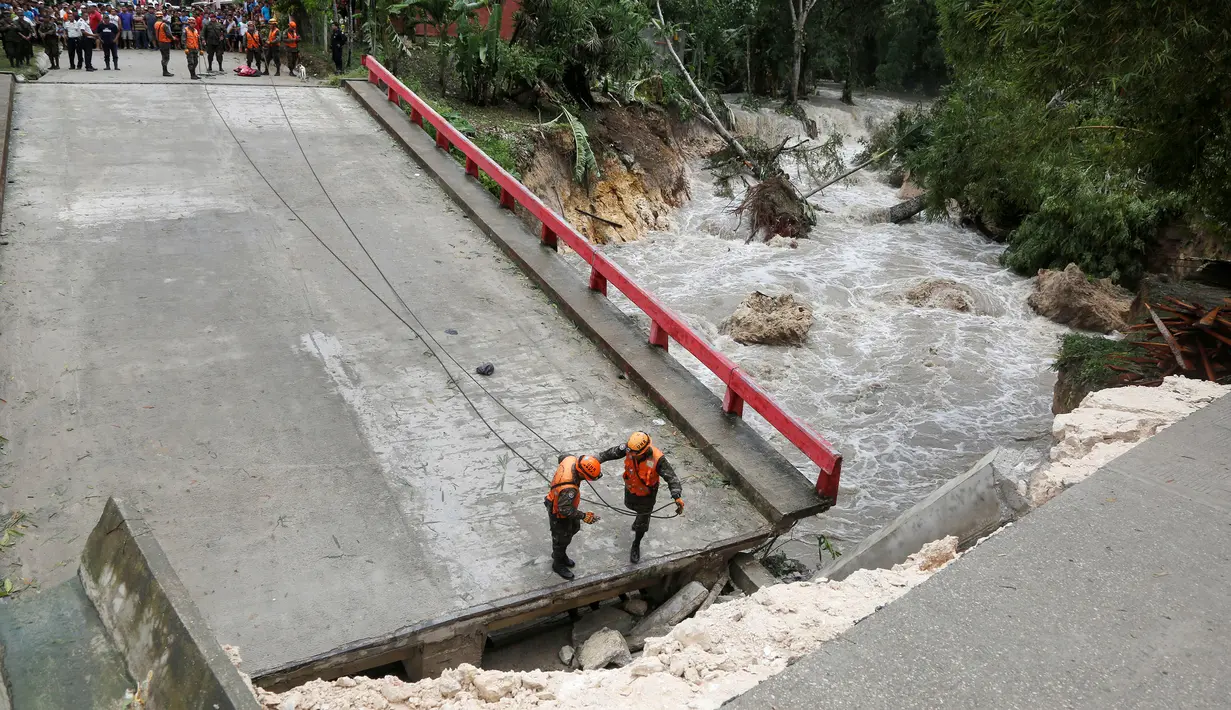 Tim penyelamat Guatemala berdiri di jembatan yang ambruk disebabkan oleh Badai Earl di Menchor de Mencos, Guatemala (4/8). Badai Earl menimbulkan hujan lebat, banjir dan angin kencang di sejumlah negara di Amerika Tengah. (REUTERS/Luis Echeverria)