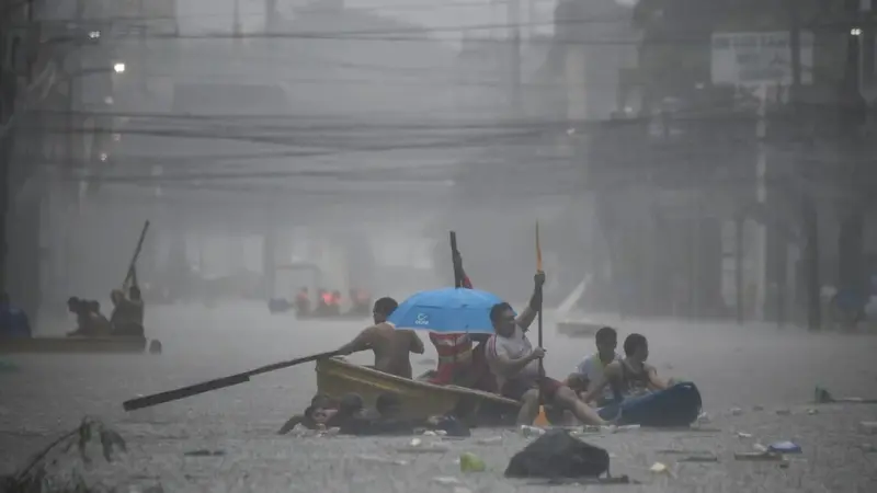 Tim penyelamat mendayung perahu mereka di sepanjang jalan yang banjir di ibu kota Filipina, Manila. [Ted Aljibe/AFP]