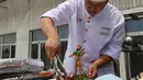 Seorang koki menyajikan makanan dengan patung mini mitos Pemanah Cina Houyi di Dezhou, Shandong Timur, Cina, 2 Agustus 2018. Koki memasak menggunakan kompor tenaga surya. (AP Foto/Fu Ting)