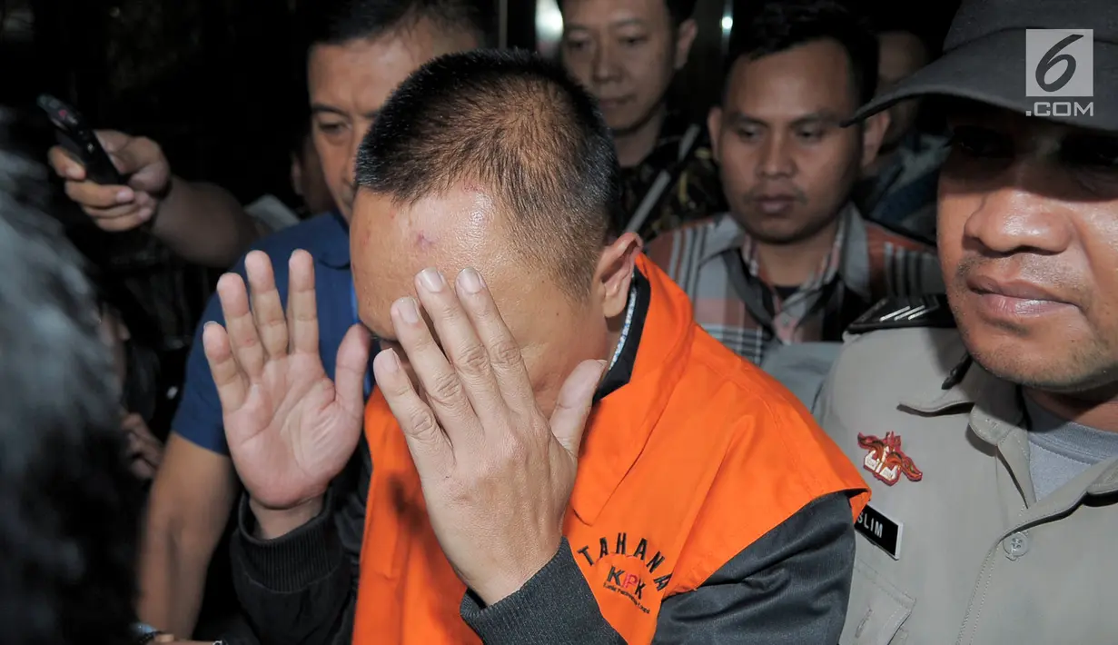 Kajari Pamekasan Rudi Indra Prasetya menutupi wajah usai menjalani periksaan di di gedung KPK, Jakarta, Kamis (3/8). Dalam OOT tersebut, KPK menangkap 11 pejabat di Kabupaten Pamekasan, Jawa Timur. (Liputan6.com/Yoppy Renato)