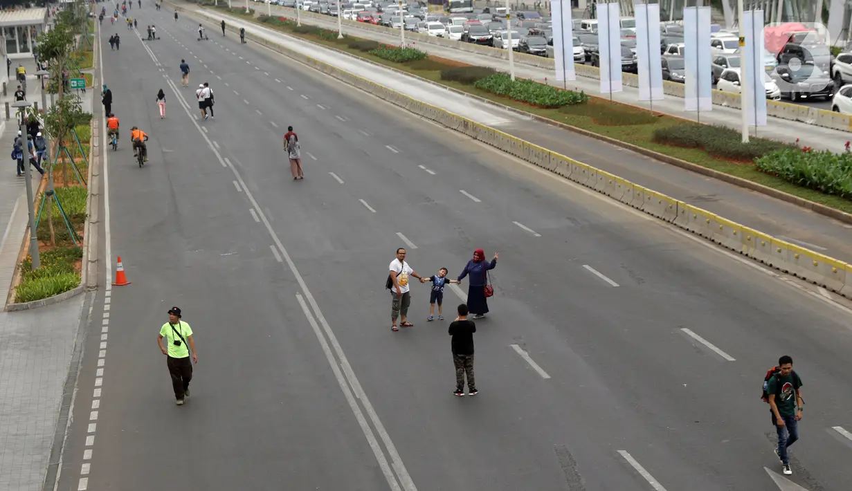 Warga memanfaatkan kondisi lengang sebagian ruas jalan Jenderal Sudirman untuk berfoto, Jakarta, Minggu (27/10/2019). Sebagian ruas Jalan Jenderal Sudirman dialihkan akibat  berlangsungnya Karnaval Kendaraan Listrik yang bertajuk Jakarta Langit Biru. (Liputan6.com/Helmi Fithriansyah)