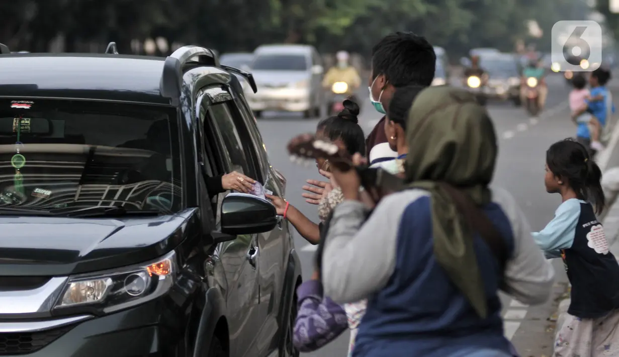 Sejumlah Penyandang Masalah Kesejahteraan Sosial (PMKS) berebut ketika pengendara membagikan uang di pinggir jalan, Jakarta, Rabu (13/5/2020). Sejumlah PMKS menantikan sedekah berupa uang, makanan, hingga sembako dari pengendara yang melintas. (merdeka.com/Iqbal S. Nugroho)