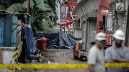 Pekerja berjaga di dekat garis polisi usai ambruknya crane pengerjaan proyek double-double track kereta api di Jatinegara, Jakarta, Minggu (4/2). Jenazah korban tewas sudah dibawa ke rumah sakit dengan mobil ambulans.  (Liputan6.com/Faizal Fanani)