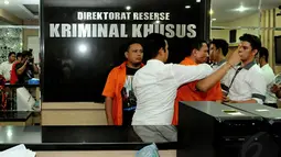 Petugas kepolisian menggiring masuk tersangka kasus pemerasan, Raden Nuh, yang berteriak saat digelar rilis di Mapolda Metro Jaya, Jakarta, Senin (3/11/2014). (Liputan6.com/Andrian M Tunay)