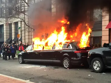 Sebuah mobil limusin dibakar oleh para pengunjuk rasa saat terpakir selama protes pelantikan Presiden Donald Trump di Washington, DC, AS, (20/1). Mobil mewah tersebut menjadi bulan-bulanan massa anti-Trump. (AP Photo/Juliet Linderman)