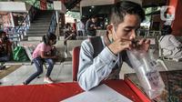 Pemudik meniup kantong saat dites dengan GeNose C19 di Terminal Kampung Rambutan, Jakarta, Minggu (23/5/2021). Pengelola Terminal Kampung Rambutan memberlakukan tes Genose sebagai syarat wajib bagi para pemudik yang baru tiba guna memutus penyebaran virus Covid-19. (merdeka.com/Iqbal S Nugroho)
