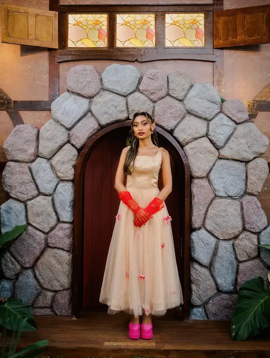 Gaun tersebut sukses ekspos kulit eksotisnya dengan paduan gloves transparan orange dan heels pink [@noviabachmid]