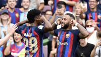 Memphis Depay (kanan) berselebrasi usai mencetak gol kedua Barcelona dalam pertandingan Liga Spanyol melawan Elche di stadion Camp Nou, Sabtu, 17 September 2022. (Josep LAGO / AFP)