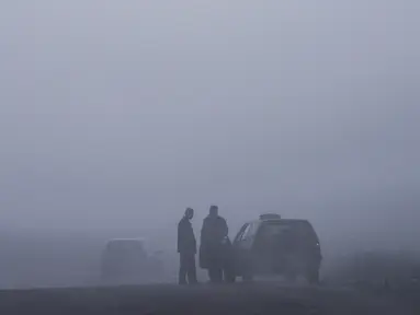 Seorang pengemudi taksi berbincang saat kabut tebal melanda kota Pristina (18/12/2019). Pristina dan banyak kota lain di Kosovo mengalami polusi udara tingkat tinggi. (AFP/Armend Nimani)