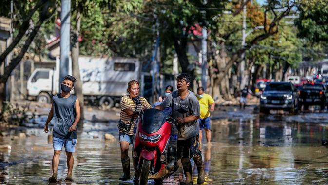 Warga berjalan di sebuah jalan yang tertutup lumpur akibat banjir yang dipicu Topan Vamco di Manila, Filipina (13/11/2020). Pemerintah Filipina pada Jumat (13/11) mengatakan Topan Vamco, yang memicu banjir besar dan tanah longsor menelan sedikitnya 14 korban jiwa. (Xinhua/Rouelle Umali)