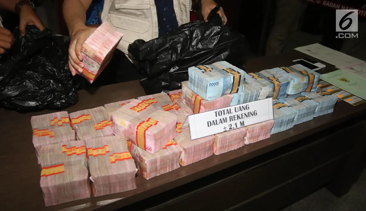Petugas BNN menunjukkan barang bukti uang hasil TPPU di Kantor BNN, Jakarta, Selasa (17/7). BNN menyita uang dari dua rekening dan satu unit rumah dengan total aset sebesar Rp 3,9 miliar. (Liputan6.com/Arya Manggala)
