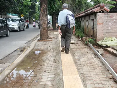 Pejalan kaki melintasi jalur pembangunan trotoar di Jalan Raya Ragunan, Jakarta, Rabu (12/10). Suku Dinas Bina Marga Jaksel mengalokasikan anggaran Rp 79 miliar untuk pembangunan dan perbaikan trotoar di 10 kecamatan Jaksel. (Liputan6.com/Yoppy Renato)