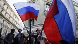 Suporter Rusia mengibarkan bendera menyambut gelaran Piala Dunia di Jalan Nikolskava, Moskow, Rabu (13/6/2018). Piala Dunia 2018 akan berlangsung pada 14 Juni hingga 15 Juli mendatang. (AP/Rebecca Blackwell)