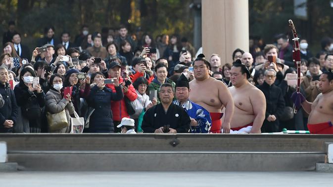 Juara Grand Sumo, Kisenosato (kedua depan) memasuki lapangan untuk melakukan upacara mengentakkan kaki menyambut tahun baru di Kuil Meiji, Tokyo, 8 Januari 2019. Ritual penyambutan tahun baru itu melibatkan tiga juara pegulat sumo (Toshifumi KITAMURA/AFP)