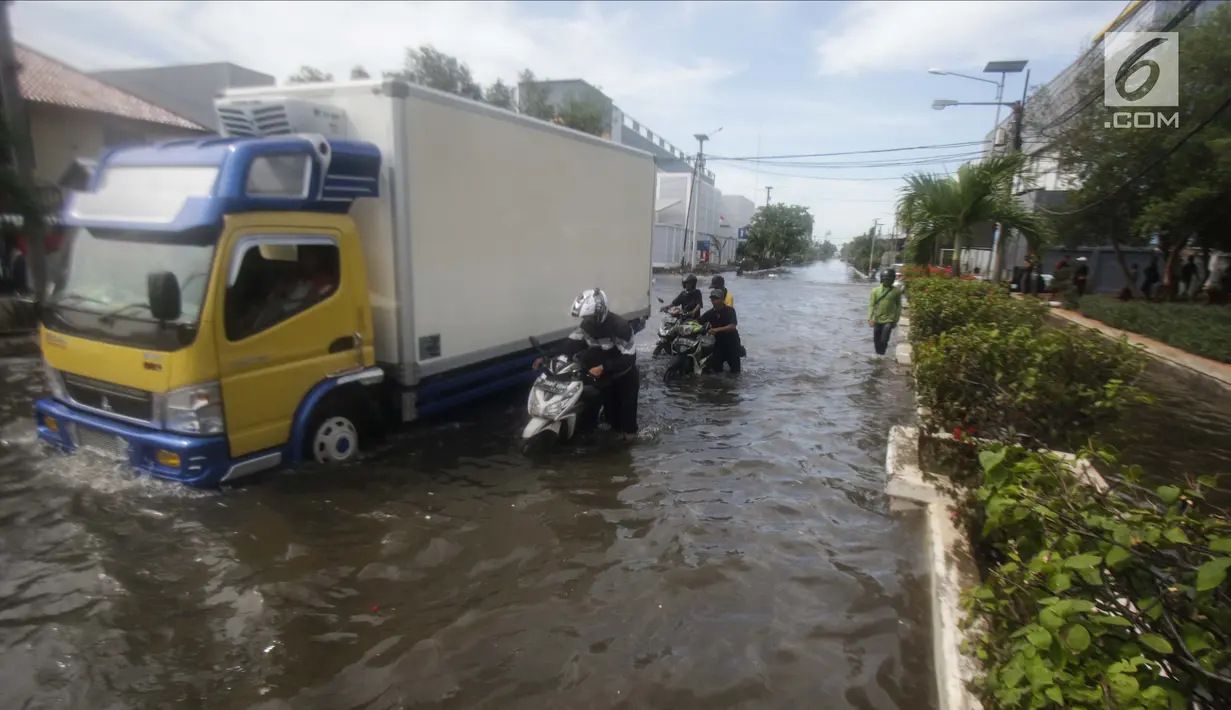 Pengendara mendorong motornya saat melintasi banjir rob di kawasan Muara Baru, Jakarta, Rabu (6/11). Air laut pasang yang terjadi mengakibatkan sejumlah wilayah dilokasi tersebut terendam banjir rob. (Liputan6.com/Faizal Fanani)