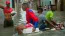 Sejumlah pria menggunakan styrofoam untuk melewati jalanan yang terendam banjir di Hanava, Kuba, Minggu (10/9). Badai irma yang melanda pantai timur Perairan Kuba pada Jumat waktu setempat menyebabkan sebagian kota terendam banjir. (AP/Ramon Espinosa)