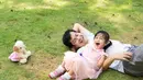 Potret ayah dan anak berbaring dan tertawa bersama dengan penuh kebahagiaan saat bermain di atas hamparan rumput yang hijau. Gemes sekali, ya, melihatnya. (SUKJAI PHOTO/ Shutterstock.com)