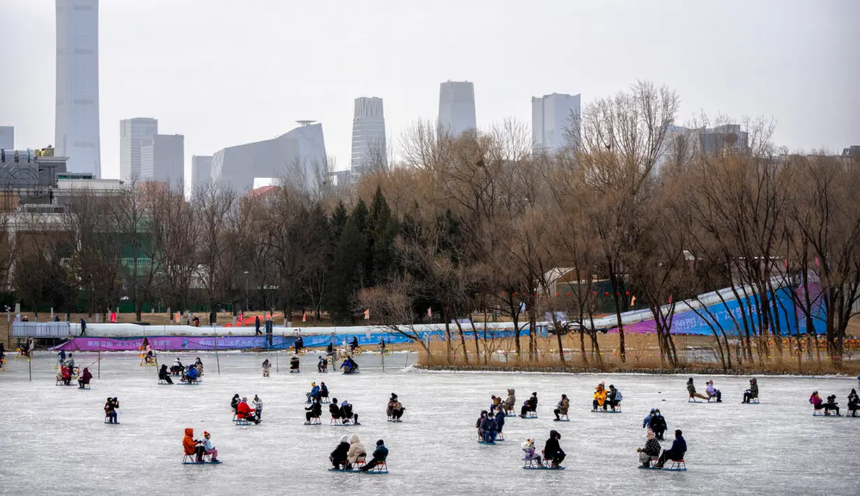Orang-orang menggunakan kursi yang dimodifikasi untuk meluncur melintasi es dalam kolam saat pekan liburan Tahun Baru Imlek di taman umum selama pekan liburan Tahun Baru Imlek di Beijing, China, Kamis (26/1/2023). (AP Photo/Mark Schiefelbein)