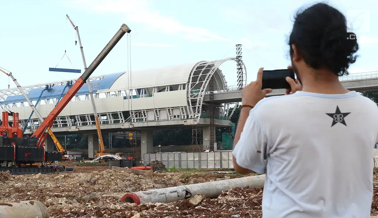 Seorang pria mengabadikan suasana pembangunan stasiun LRT di kawasan Ciracas, Jakarta, Sabtu (23/3). Pada tahun 2019, pemerintah menganggarkan dana APBN untuk infrastruktur sebesar Rp415 triliun, naik 1,04% dari anggaran infrastruktur tahun sebelumnya. (L