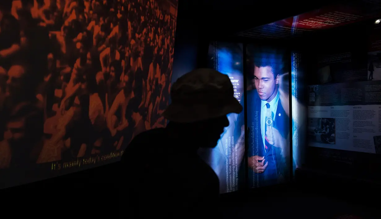 Pengunjung melintas di depan foto petinju legendaris Muhammad Ali di Muhammad Ali Center, Louisville, Kentucky (5/6). Muhammad Ali Center ini memiliki enam lantai dengan luas 8.988 meter persegi. (AFP PHOTO/Brendan Smialowski)