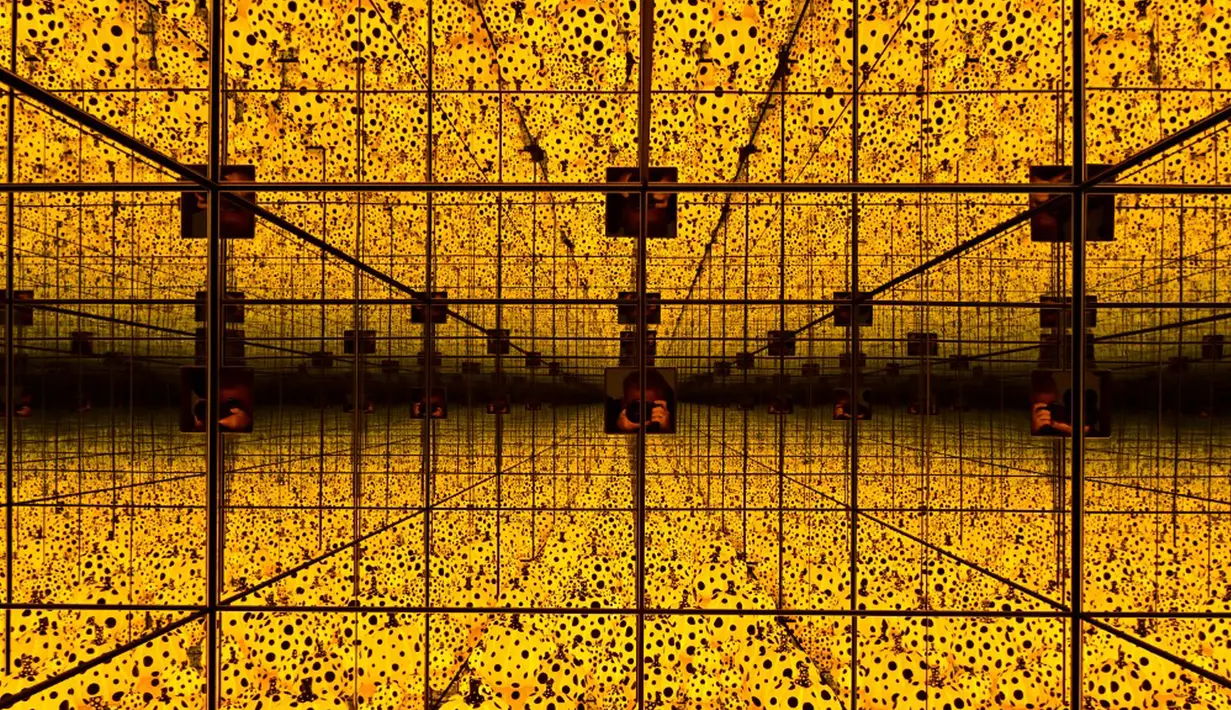 Seorang fotografer mengambil foto instalasi seni berjudul 'The spirit of the pumpkins descended into the heavens' (2015) karya seniman kontemporer Jepang Yayoi Kusama dalam pameran Yayoi Kusama: A Retrospective di Atrium Martin Gropius Bau, Berlin, Jerman, Selasa (19/5/2021). (John MACDOUGALL/AFP)