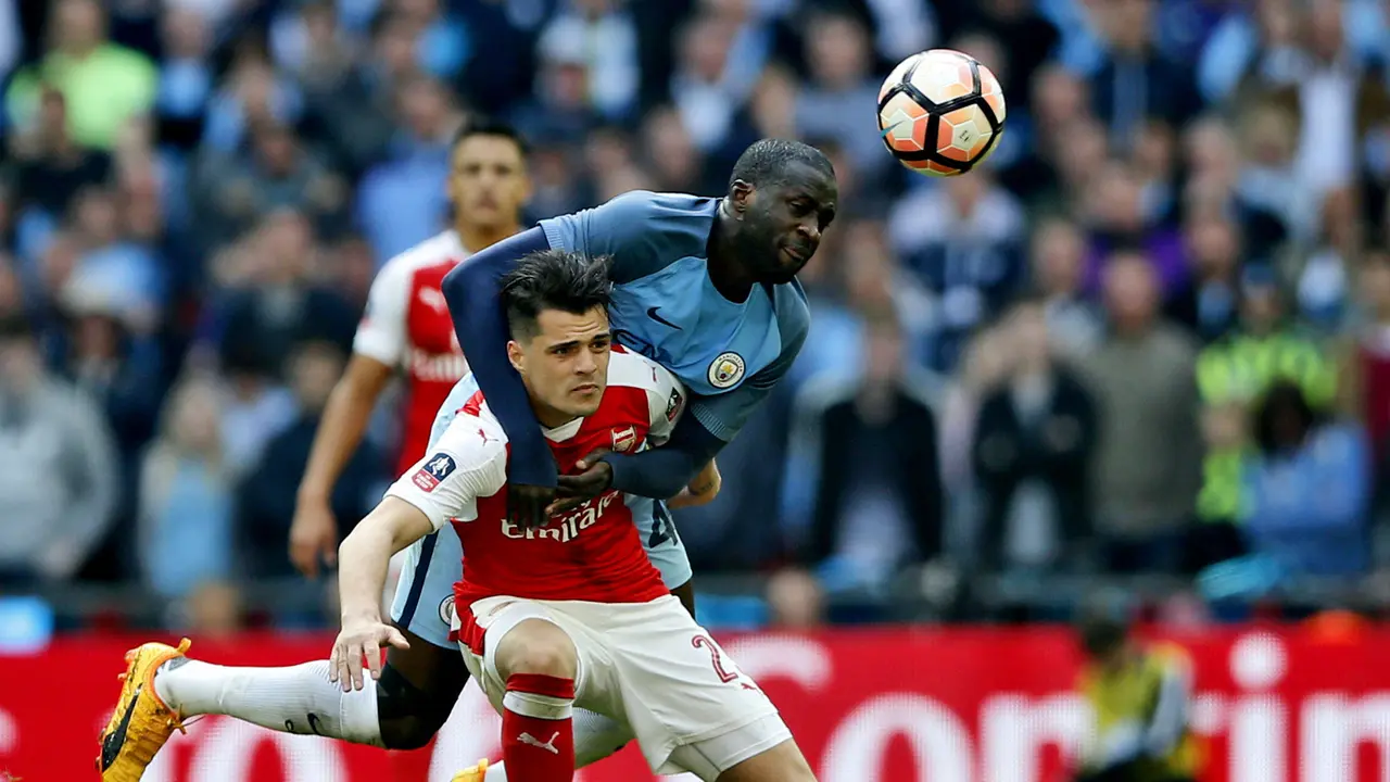 Pemain Manchester City, Yaya Toure (belakang), berebut bola dengan gelandang Arsenal, Granit Xhaka (bawah), pada semifinal Piala FA di Wembley , London, Minggu (23/4/2017). Manchester City kalah 1-2. 