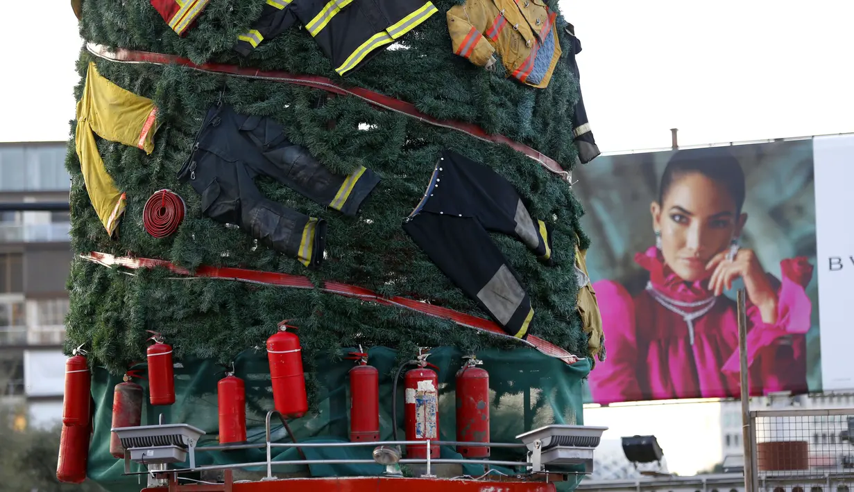 Pakaian dan peralatan milik petugas pemadam kebakaran yang tewas dalam ledakan di Pelabuhan Beirut diletakkan pada sebuah pohon Natal di Beirut, Lebanon (20/12/2020). Pohon Natal ini didirikan juga bentuk penghormatan kepada mereka yang tewas dalam ledakan tersebut. (Xinhua/Bilal Jawich)