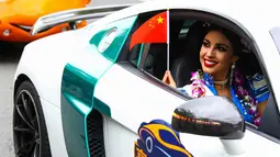 Seorang kontestan Miss World tersenyum sambil membawa bendera China saat mengikuti pawai menggunakan supercar di Sanya, Provinsi Hainan, China, (7/11). Pawai ini membuka kontes kecantikan Miss World ke-67. (AFP Photo/Str/China Out)