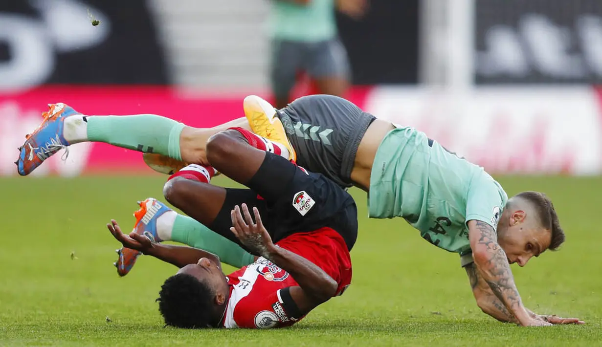 Pemain Everton, Lucas Digne, terjatuh saat berebut bola dengan pemain Southampton, Kyle Walker-Peters, pada laga Liga Inggris di Stadion St. Mary's Minggu (25/10/2020). Southampton menang dengan skor 2-0. (AP Photo/Frank Augstein, Pool)
