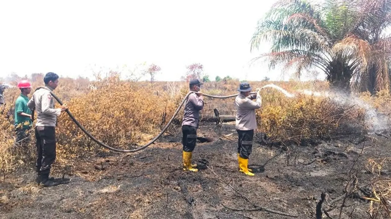 Personel Polda Riau di Siak mendinginkan lahan setelah dipadamkan beberapa hari lalu.