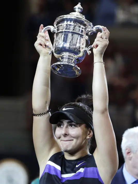 Petenis Kanada, Bianca Andreescu (19) mengangkat Piala AS Terbuka 2019 usai mengalahkan Serena Williams dari AS di final tunggal putri di New York (7/9/2019). Andreescu juga menjadi remaja pertama yang memenangi grand slam setelah Maria Sharapova 13 tahun lalu. (AP Photo/Adam Hunger)