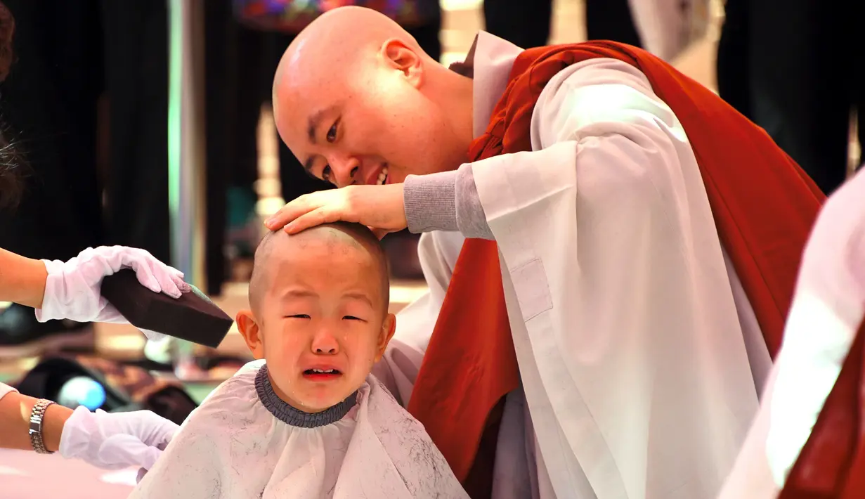 Seorang anak dicukur saat upacara berjudul 'Anak-anak Menjadi Buddha Monks', di kuil Jogye, Seoul, Rabu (19/4). Setelah upacara anak-anak akan tinggal di kuil selama dua minggu untuk mengikuti perayaan ulang tahun Buddha. (AFP PHOTO / JUNG Yeon-Je)
