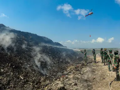 Anggota Raider 900/SBW TNI AD dan helikopter Badan Nasional Penanggulangan Bencana (BNPB) berupaya untuk memadamkan kebakaran sampah di Tempat Pembuangan Akhir (TPA) Regional Sarbagita Suwung, Denpasar, Bali, Jumat (20/10/2023). Hingga saat ini, kebakaran yang terjadi pada Kamis (12/10) tersebut belum dapat dipadamkan. (merdeka.com/Arie Basuki)