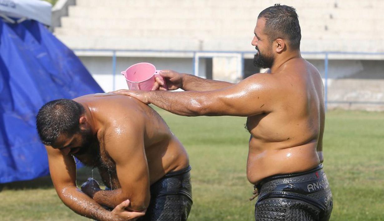 Peserta saling mengguyurkan oli sebelum bertanding. (AFP Photo/Adem Altan)