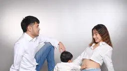 Suami Tasya Revina juga ikut dalam sesi pemotretan dengan nuansa serasi. Duduk berseberangan, ia memperlihatkan tatapan penuh cinta kepada istrinya yang tengah mengandung. Anak pertama mereka pun tampak antusias menyentuh perut sang ibu, seolah menyambut kehadiran calon adiknya. (Liputan6.com/IG/@tasyarevina)