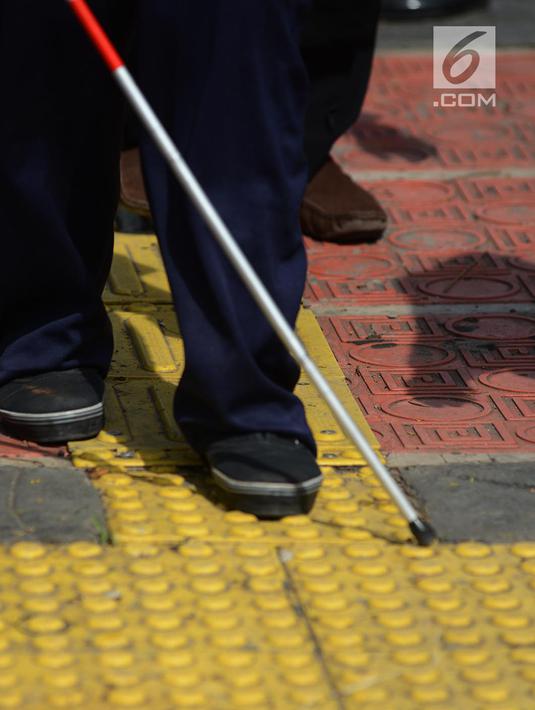 Penyandang disabilitas netra berjalan menyusuri ubin pemandu saat kampanye kegunaan ubin pemandu di trotoar Rawamangun, Jakarta, Selasa (2/4/2019). Kegiatan tersebut untuk memberikan pemahaman kepada masyarakat luas agar tidak terjadi penyalahgunaan di area ubin pemandu. (merdeka.com/Imam Buhori)