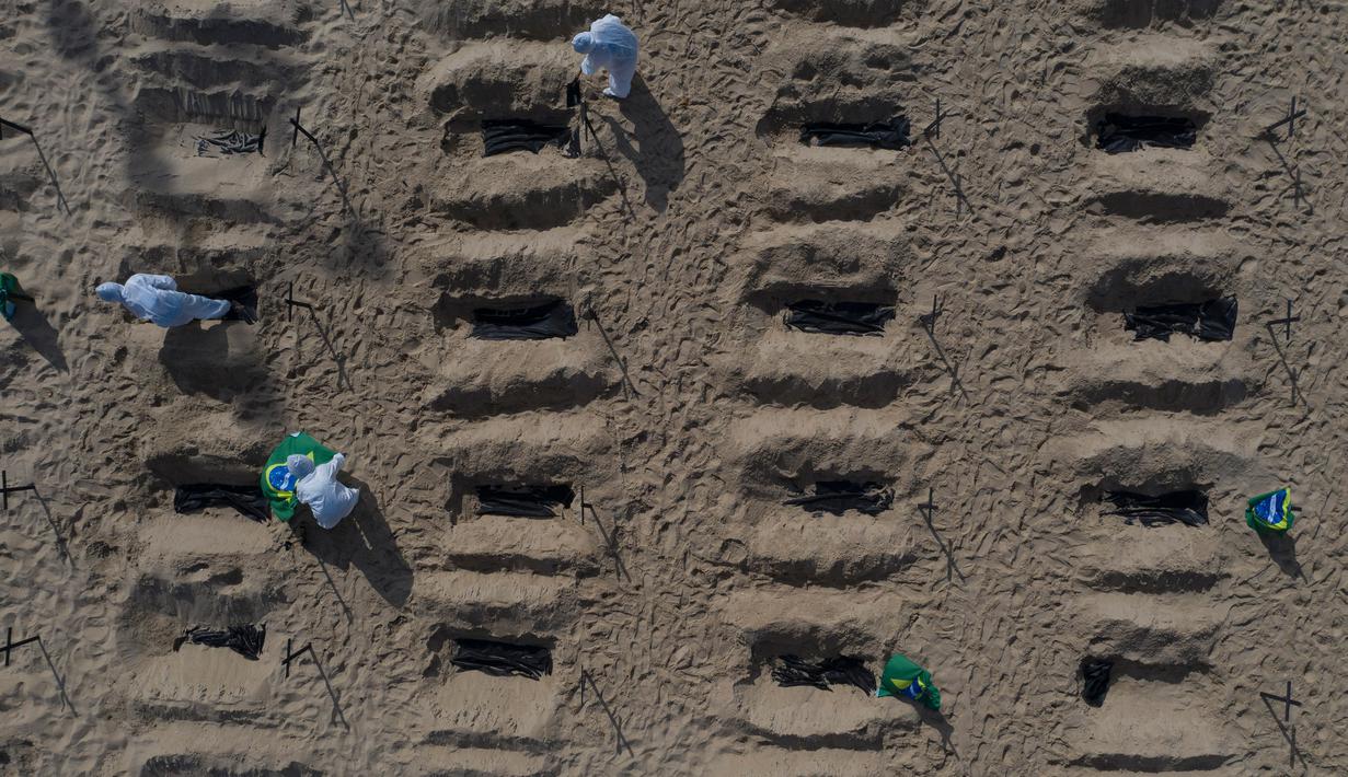 Aktivis LSM Rio de Paz menggali kuburan sebagai bentuk protes di pantai Copacabana, Rio de Janeiro, Kamis (11/6/2020). Kuburan-kuburan dengan simbol salib hitam yang dihiasi bendera Brasil kecil itu untuk mengenang puluhan ribu pasien corona yang meninggal di negara tersebut. (AP Photo/Leo Correa)