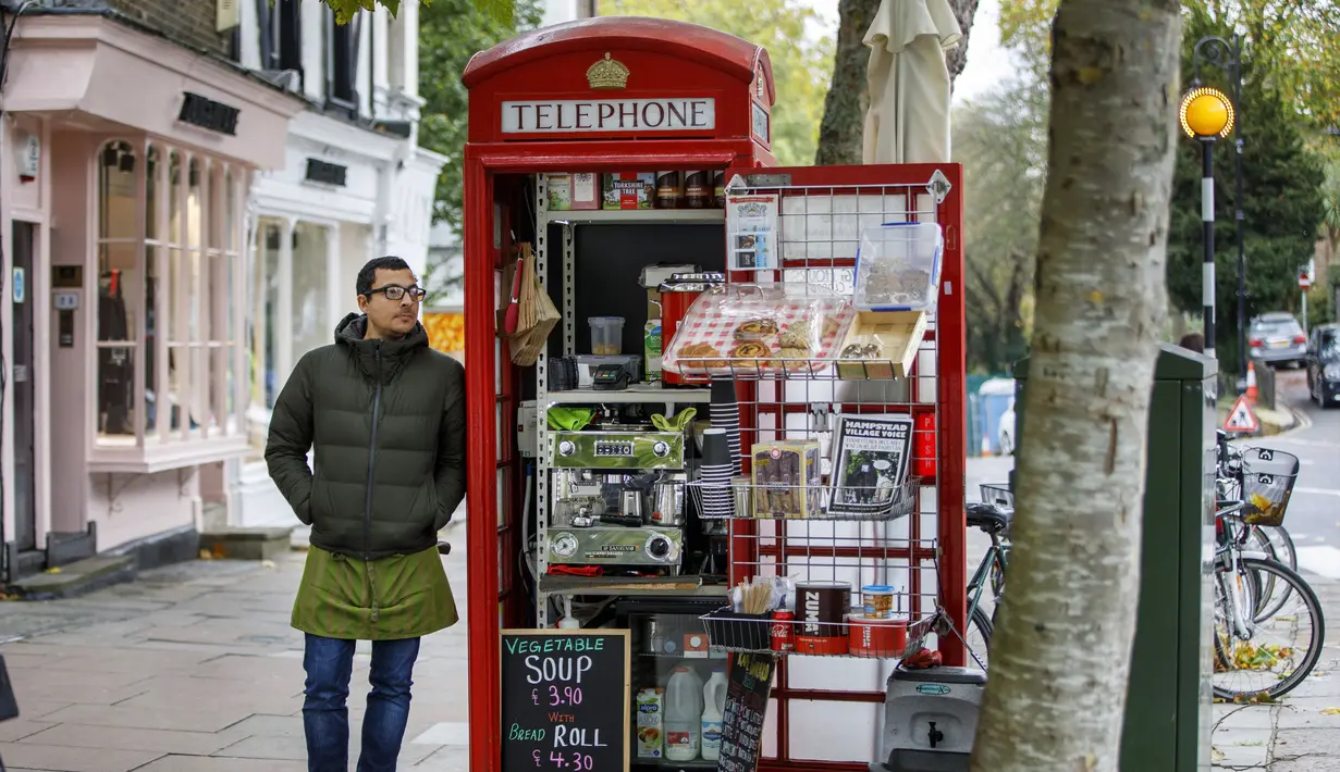 Umar Khalid berpose di luar kotak telepon merah tempat dia mengelola kedai kopi di Hampstead Heath, London Utara (20/12). Kotak telepon umum merah klasik di Inggris ini dialihfungsikan untuk berbagai jenis kegunaan baru. (AFP Photo/Tolga Akmen)