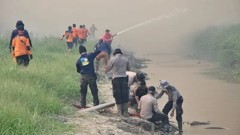 Personel Polres Pelalawan berusaha memadamkan titik api yang menyebabkan kabut asap tebal.