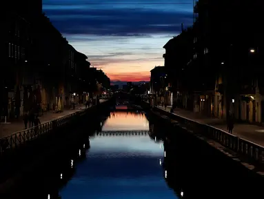 Beberapa orang berjalan di Kanal Naviglio Grande, Milan, Italia, Selasa (10/3/2020). Tak seperti biasanya yang selalu ramai, merebaknya virus corona (COVID-19) membuat salah satu tempat favorit bagi kehidupan malam di Milan tersebut kini terlihat sepi. (AP Photo/Antonio Calanni)